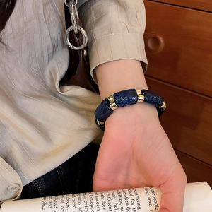 Detailed shot of dark blue starry acrylic beads and gold spacers on a geometric bracelet