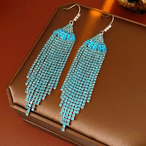 Detailed view of blue rhinestone tassel earrings with silver hooks on a jewelry box