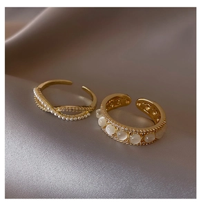 Macro detail of gold adjustable rings with pearls, cat eye stone, and pave zircon details