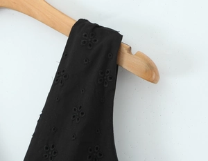 Détail de la robe en coton noir avec broderie florale et finitions ajourées élégantes