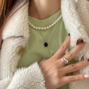 Detail of 925 silver puzzle necklace with pearl strand and ring worn on green shirt