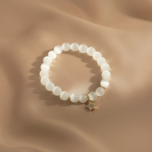 Macro detail of cat eye stone beaded bracelet with gold star charm and micro diamonds