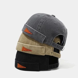 Trois bonnets docker en coton délavé gris, kaki et noir avec un écusson orange