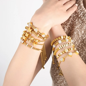Fashionable gold-plated beaded bracelets with heart and butterfly charms on a model