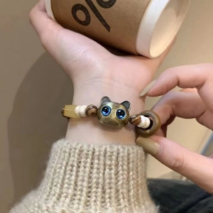 Detail of beaded bracelet featuring bronze cat head and wooden beads on person wrist