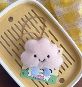 Close-up of a pink plush cloud keychain with blue legs and cute embroidered face
