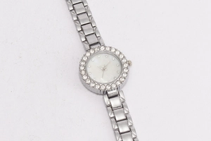 Nahaufnahme einer silbernen Armbanduhr mit Strass-Lünette und weißem Perlmuttzifferblatt