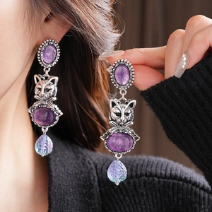 Macro view of vintage silver cat earrings with purple oval gems and light blue drops