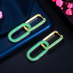 Macro shot of gold-plated hoop earrings with micro-paved green cubic zirconia stones