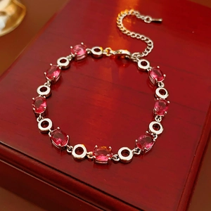 Detailed shot of silver bracelet featuring red oval zircon stones on a mahogany jewelry box