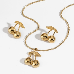 Detailed view of polished gold cherry-shaped jewelry set including earrings and necklace
