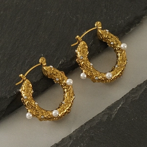 Détail de créoles C dorées 18k avec perles et cristaux sur métal à texture martelée