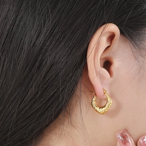 Minimalist gold-plated C-shaped textured earrings worn by a model in a close-up view