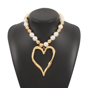 Detailed view of oversized hollow gold heart pendant with mixed white faux pearls on model