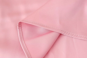 Dettaglio macro del tessuto di raso rosa con texture liscia e cuciture a doppio filo