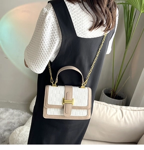Lifestyle shot of woman carrying a two-tone khaki and cream crossbody bag with gold chain