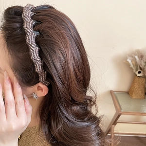 Detail of coffee brown knitted wave headband styled on model in warm indoor setting