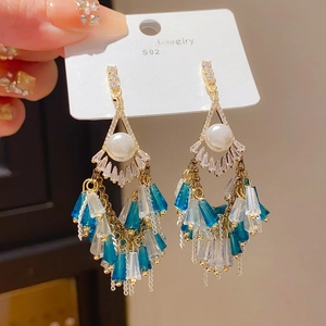 Detail of ethnic tassel earrings with gold frame, blue crystals, and S925 silver needle