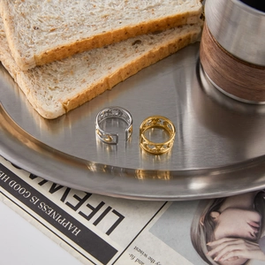 Close-up of gold and silver moon star hollow rings on a minimalist metal tray