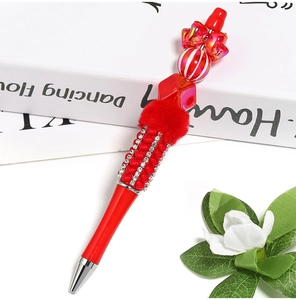 Detail of DIY bead pen with red white stripes pumpkin beads and velvet pom pom charm