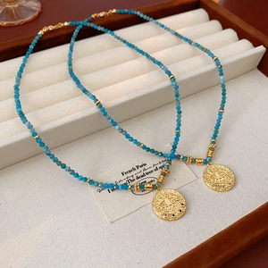 Detail of blue beaded necklace with a golden evil eye pendant on velvet jewelry display