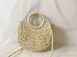 Detailed texture of beige handmade woven straw handbag with round handle on lace background