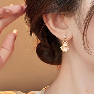 Close-up of pink gourd earrings with white pearls and gold leaves on a model