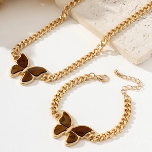Close-up of golden butterfly pendant with brown stone on cuban chain necklace set
