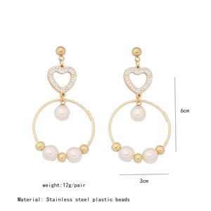 Detail view of heart-shaped pearl drop earrings in gold finish with 6cm length dimensions
