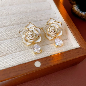 Gros plan sur les boucles d'oreilles vintage en or avec roses émaillées et zircons