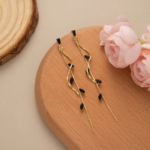 Elegant gold long leaf tassel earrings with black marquise drops on wooden display