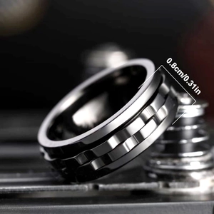 Close-up of black 8mm wide anxiety spinner ring with industrial metal background