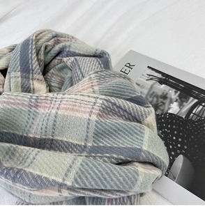 Detailed close-up of the woven herringbone texture on a soft plaid winter scarf