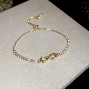 Macro shot of gold infinity bracelet with sparkling zircon stones and adjustable chain