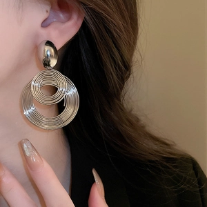 Close-up of silver geometric layered hoop earrings on model with high metallic finish