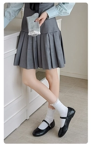 Détail de chaussettes blanches à volants portées avec des chaussures Mary Jane et jupe