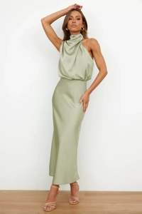 Detail of sage green satin dress showing elegant halter neck and glossy fabric texture