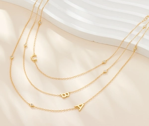 Detailed view of gold S925 silver necklaces with letter pendants and zircon accents