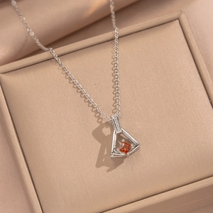 Silver skirt pendant necklace with red zircon on beige jewelry box and silk backdrop
