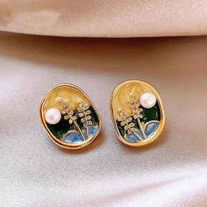 Macro detail of French vintage pearl flower earrings with colorful enamel on silk