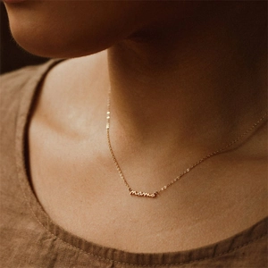 Collana minimalista in argento S925 dorato con scritta mama indossata su una modella