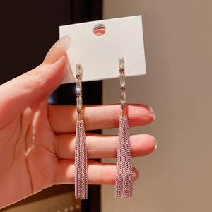 Detailed close-up of long gold fringe earrings with pink beads and sparkling zircons
