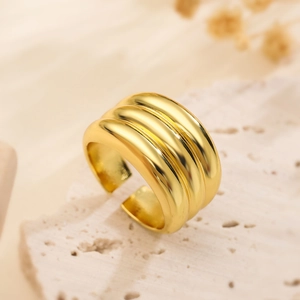 Minimalist gold plated triple band open ring displayed on natural beige stone texture