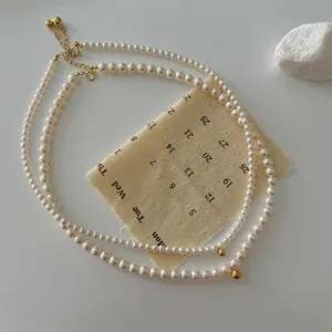 Detail of two-piece white pearl necklace set with gold sphere charm and lobster clasp