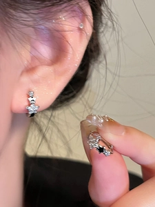 Primer plano de pendientes de estrella plateados con circonitas mostrados en la oreja
