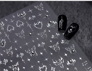 Macro detail of silver gothic nail stickers with chrome heart and butterfly star patterns