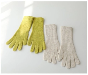 Detail of yellow-green and beige rabbit fur knit gloves with ribbed cuffs on white background
