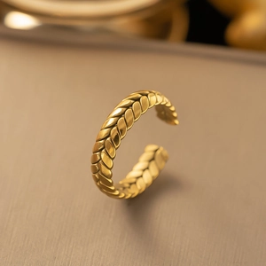 Adjustable golden braided texture ring in 18K gold plated stainless steel on metal background