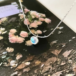 Detail of 925 silver necklace featuring a round opal pendant against a floral background