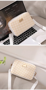 Detail view of a white vintage crossbody bag with yellow geometric patterns and gold hardware